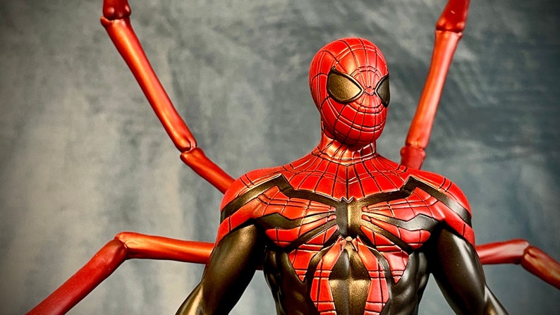 May include: A red and black Spider-Man action figure with long, red, articulated arms. The figure has a detailed, black and red suit with a spider symbol on the chest.