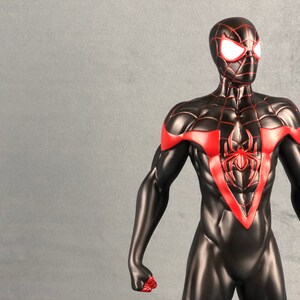 May include: A black and red action figure of Spider-Man with a red spider symbol on the chest. The figure has white eyes and is posed with its arms out.