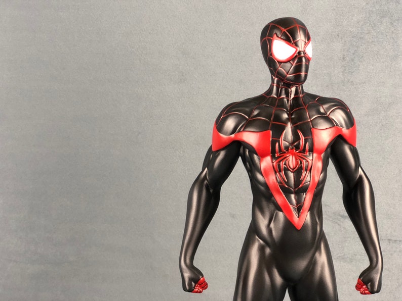 May include: A black and red action figure of Spider-Man with a red spider symbol on the chest. The figure has white eyes and is posed with its arms out.