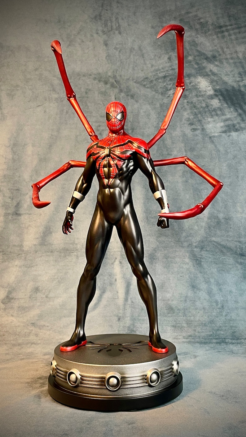 May include: A red and black action figure of Spider-Man with long red spindly arms. The figure is standing on a round base with a spider symbol in the center.