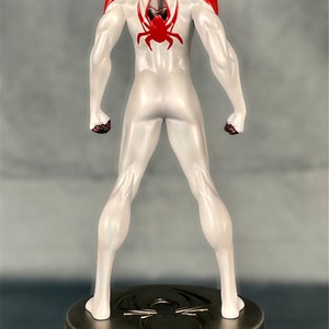 May include: A white and red action figure of Spider-Man standing on a black and silver base. The figure is posed with its arms at its sides and its legs slightly apart. The figure has a black spider symbol on its back.