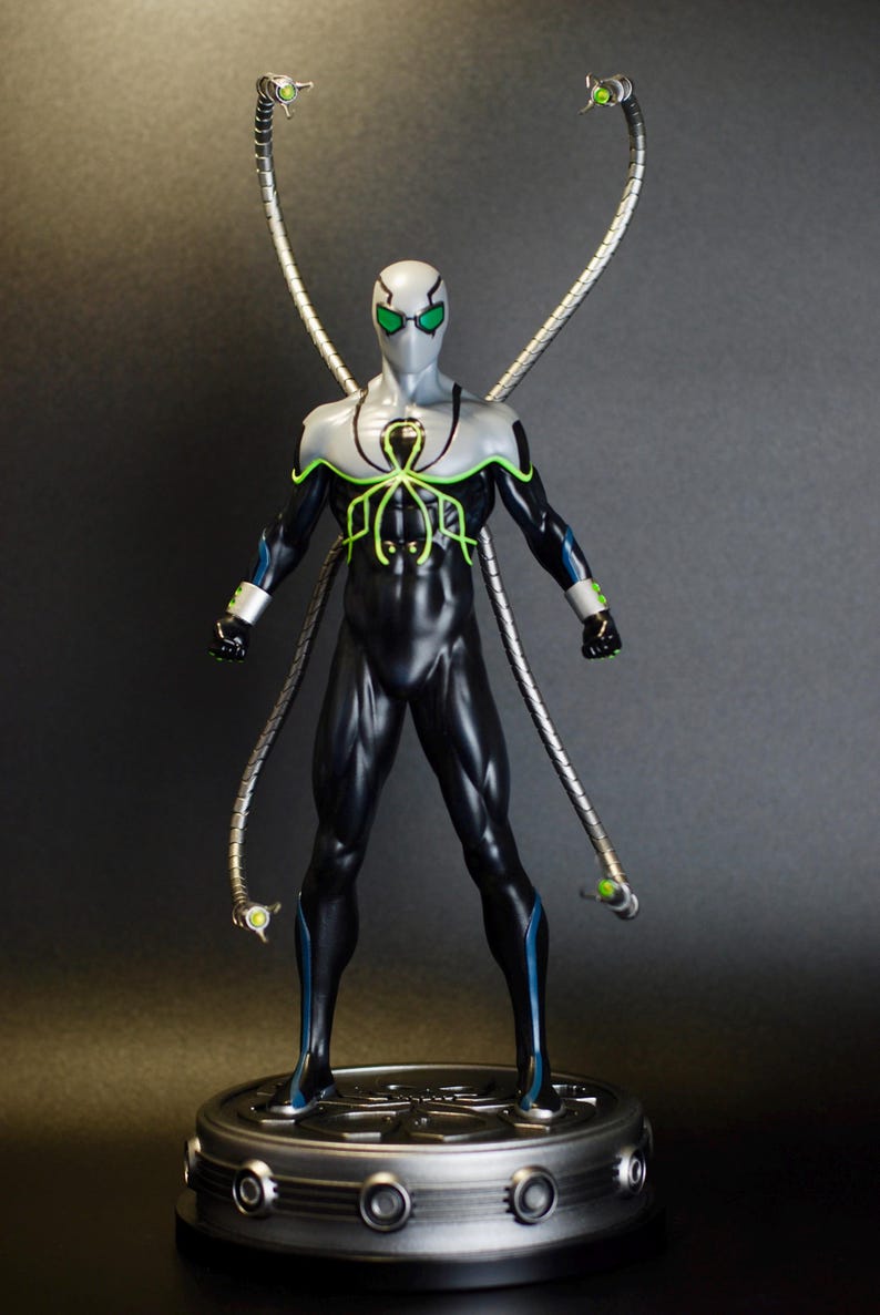 Puede incluir: Una figura de acci&oacute;n negra y verde de un superh&eacute;roe con cuatro brazos mec&aacute;nicos. La figura est&aacute; de pie sobre una base plateada con un dise&ntilde;o circular.