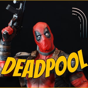 May include: A Deadpool figurine in a red and black costume, holding a black gun. The word "DEADPOOL" is in yellow letters with a black outline. The background is black.
