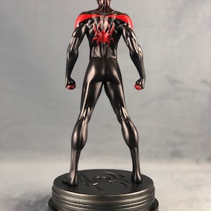 May include: Black and red Spider-Man action figure standing on a black base with a spider logo. The figure is posed with its arms raised and fists clenched.