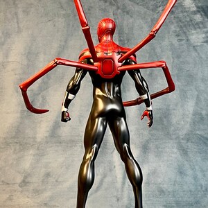 May include: A black and red action figure of Spider-Man with red, articulated spider legs. The figure is standing on a black and silver base with a spider web design.
