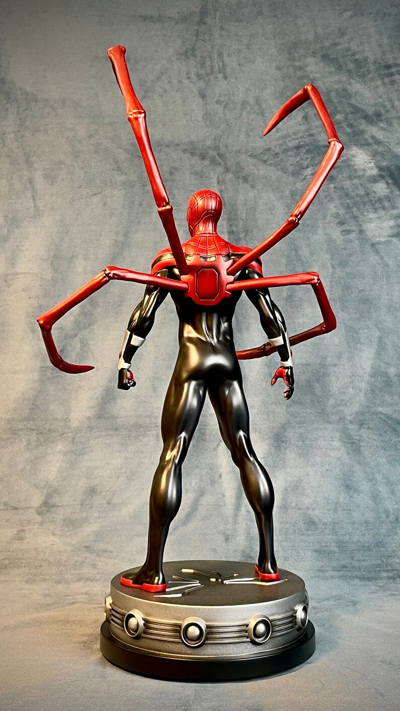May include: A black and red action figure of Spider-Man with red, articulated spider legs. The figure is standing on a black and silver base with a spider web design.
