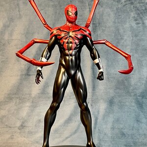 May include: A red and black action figure of Spider-Man with long red arms. The figure is standing on a silver base with a spider logo.