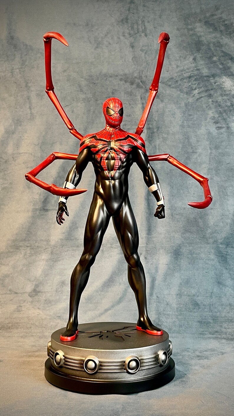May include: A red and black action figure of Spider-Man with long red arms. The figure is standing on a silver base with a spider logo.