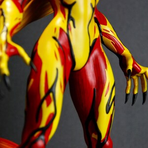 May include: A figurine with a fiery design. The figure's body is painted with red and yellow flames, with black accents. The hands have long black claws. The figure's wings are yellow and orange.