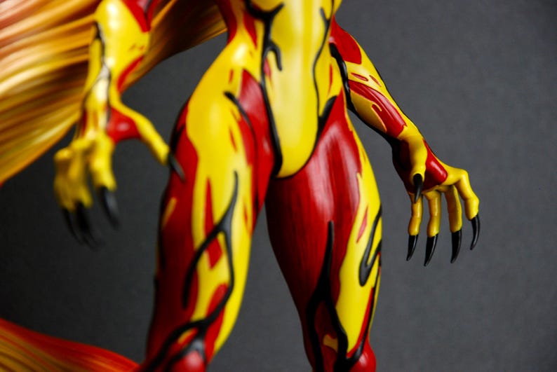 May include: A figurine with a fiery design. The figure's body is painted with red and yellow flames, with black accents. The hands have long black claws. The figure's wings are yellow and orange.