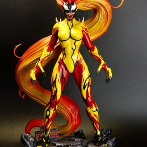 May include: A detailed figurine of a female character with a fiery red and yellow color scheme. The figure has a yellow bodysuit with red accents, long flowing hair, and a menacing facial expression. The figure stands on a rocky base.
