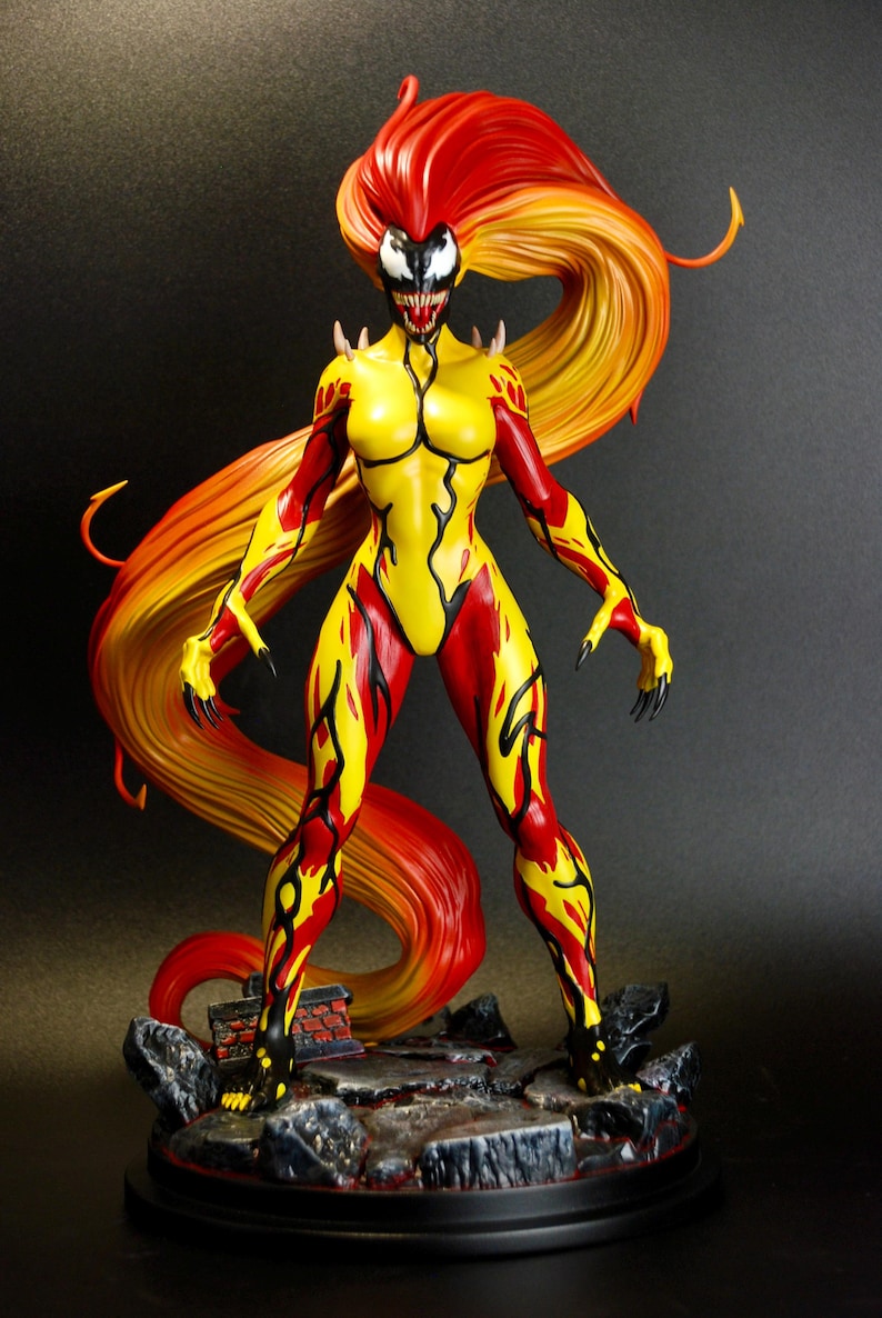 May include: A detailed figurine of a female character with a fiery red and yellow color scheme. The figure has a yellow bodysuit with red accents, long flowing hair, and a menacing facial expression. The figure stands on a rocky base.