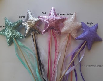 May include: Five star-shaped wands with glitter fabric and ribbon tails. The wands are in the colors blue, silver, pink, iridescent white, and purple.