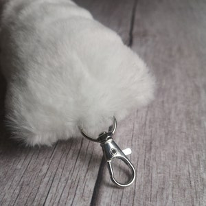 May include: A white fluffy keychain with a silver metal clasp.