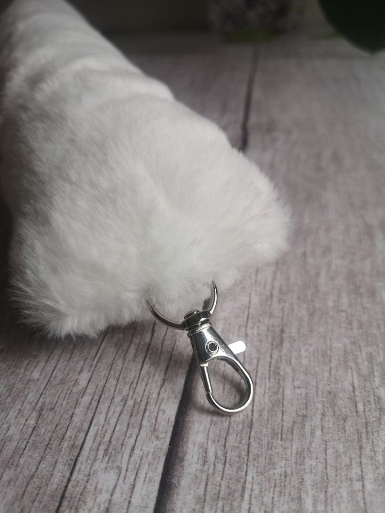 May include: A white fluffy keychain with a silver metal clasp.
