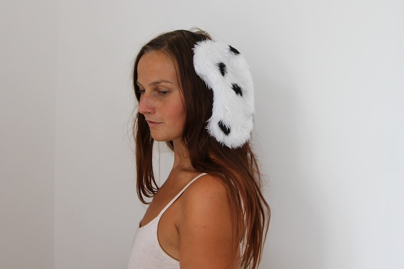 A pretty girl modelling Dalmatian dog ears, kidney bean shaped white faux fur with small black spots. Sewn onto a thin black hairband.