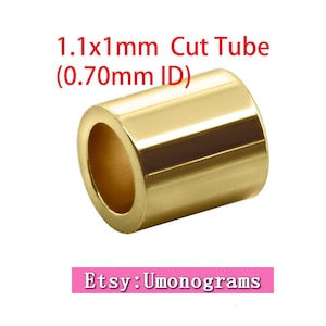 Puede incluir: Un tubo de metal de color dorado con un diámetro exterior de 1,1 mm x 1,1 mm y un diámetro interior de 0,70 mm. El tubo está cortado y tiene un acabado liso y brillante. El texto "1.1x1mm Cut Tube (0.70mm ID)" es visible sobre el tubo. El texto "Etsy: Umonograms" es visible debajo del tubo.