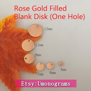 Op de afbeelding: Assortiment van rose gold gevulde, lege metalen schijven met een gat in het midden. De schijven zijn gerangschikt op grootte, van de grootste tot de kleinste, waarbij de grootste schijf een diameter van 13 mm heeft en de kleinste een diameter van 4 mm. De schijven liggen op een bruine en oranje bladeren achtergrond.