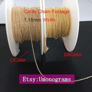 May include: Two spools of gold cable chain, one with a lighter colour and one with a darker colour. The chain is 1.18mm wide. The text "Cable Chain Footage 1.18mm Width" is printed on the spools. The text "Etsy: Umonograms" is printed below the spools.
