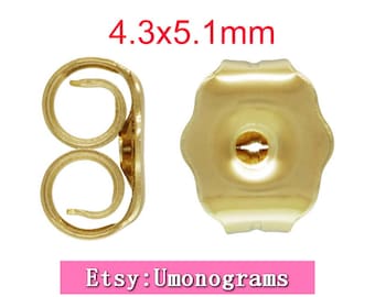 May include: Gold-toned earring backs, 4.3 x 5.1 mm in size. The backs have a rounded, scalloped edge and a small hole in the center.