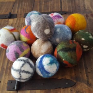 May include: A collection of colorful felt balls, each with a unique pattern. The balls are made of wool and are approximately 2 inches in diameter. They are perfect for adding a touch of whimsy to any room.
