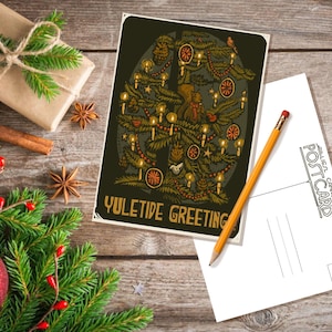May include: A vintage-style postcard featuring a stylized illustration of a Christmas tree with ornaments, candles, and a bird. The text "Yuletide Greeting" is printed at the bottom of the postcard.