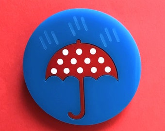 Lluvia broche acrílico, paraguas rojo con lunares blancos, bajo un aguacero, sobre un fondo de cielo azul