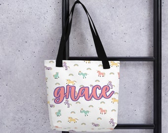 May include: A white tote bag with black handles and a colorful unicorn pattern. The bag has the name "grace" written in pink and purple letters.