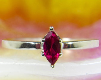 May include: A silver ring with a marquise-shaped ruby gemstone.
