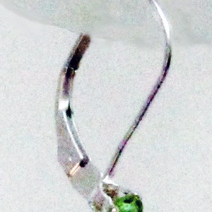 May include: Silver earring with a green gemstone. The earring has a simple, elegant design.