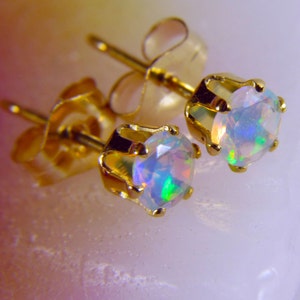 May include: A pair of gold stud earrings with iridescent opal gemstones. The earrings have a simple, classic design.
