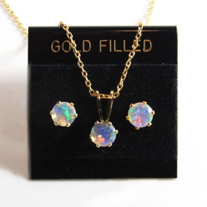 May include: A gold filled necklace and earrings set with opal stones. The necklace has a simple chain and a round pendant with an opal stone. The earrings are stud earrings with round opal stones.