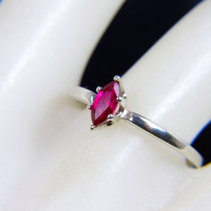 May include: A silver ring with a marquise-shaped ruby gemstone.