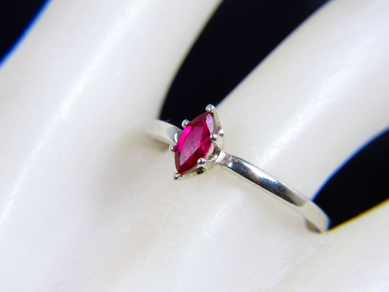 May include: A silver ring with a marquise-shaped ruby gemstone.
