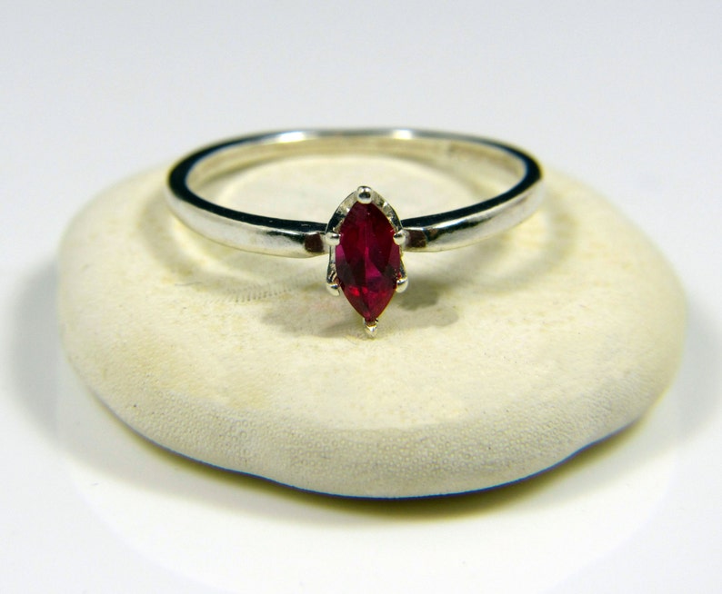 May include: A silver ring with a marquise-shaped ruby gemstone.
