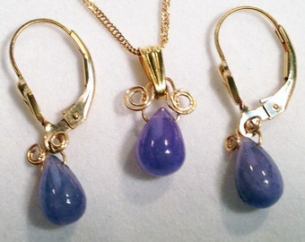 Peut inclure: Un ensemble de boucles d'oreilles et d'un collier en or avec des pierres en forme de larme violettes. Les boucles d'oreilles ont une fermeture à crochet et le collier a une chaîne délicate.