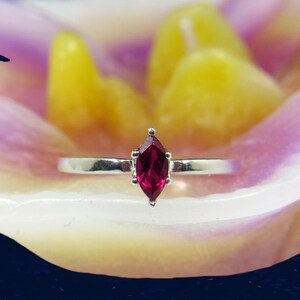 May include: A silver ring with a marquise-shaped ruby gemstone.