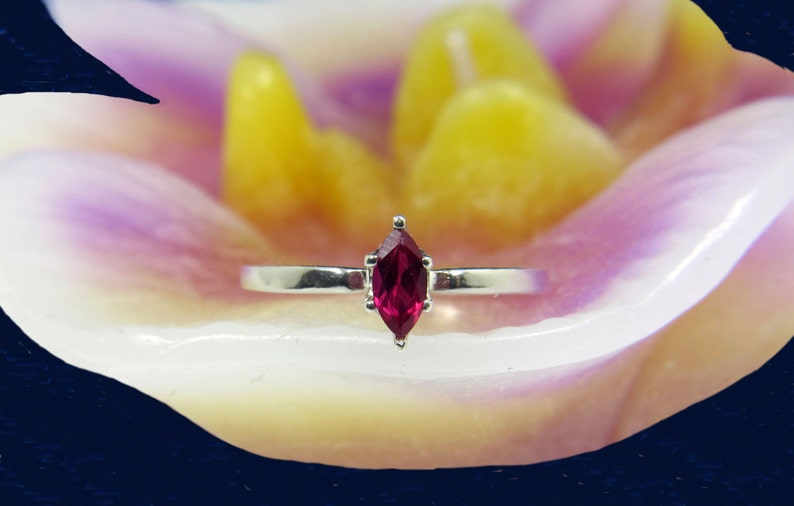 May include: A silver ring with a marquise-shaped ruby gemstone.