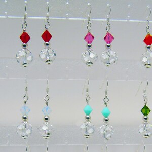 Puede incluir: Un conjunto de 10 pares de pendientes de plata con gotas de cristal. Los pendientes presentan cuentas de cristal de diferentes colores, incluyendo rojo, rosa, azul, turquesa y verde.