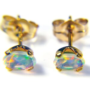 May include: A pair of gold stud earrings with iridescent opal gemstones.