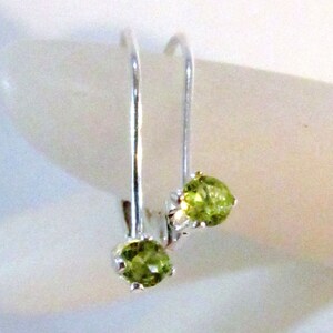 May include: A pair of silver earrings with green gemstone accents. The earrings are simple and elegant, perfect for everyday wear.