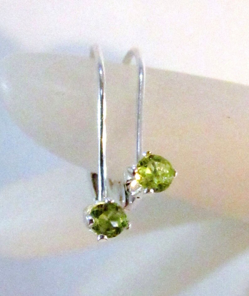 May include: A pair of silver earrings with green gemstone accents. The earrings are simple and elegant, perfect for everyday wear.