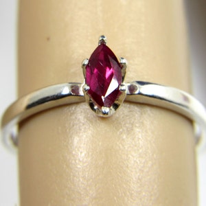 May include: A silver ring with a marquise-shaped ruby gemstone.