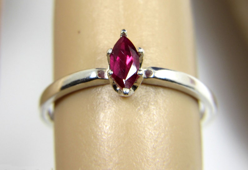 May include: A silver ring with a marquise-shaped ruby gemstone.
