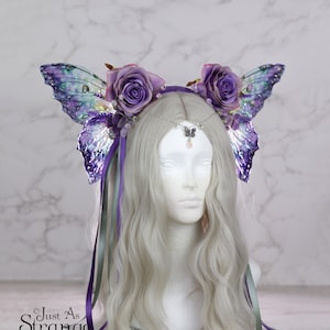 May include: Purple and green iridescent butterfly wings with purple roses and green and purple ribbons attached to a headband.