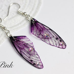 May include: Purple and silver fairy wing earrings with clear crystal accents. The earrings are on a white background.