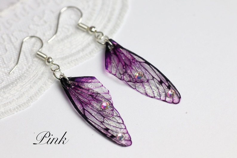 May include: Purple and silver fairy wing earrings with clear crystal accents. The earrings are on a white background.