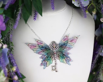 May include: A silver necklace with a colorful butterfly pendant featuring a keyhole design. The butterfly wings are iridescent and have a watercolor effect. The pendant is adorned with small rhinestones.