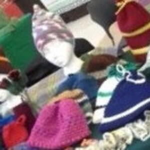 May include: A selection of knitted hats in various colours and designs. The hats include beanies, some with stripes, and others with unique patterns. The hats are displayed on mannequin heads, showcasing their shape and design.