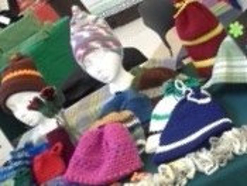 May include: A selection of knitted hats in various colours and designs. The hats include beanies, some with stripes, and others with unique patterns. The hats are displayed on mannequin heads, showcasing their shape and design.